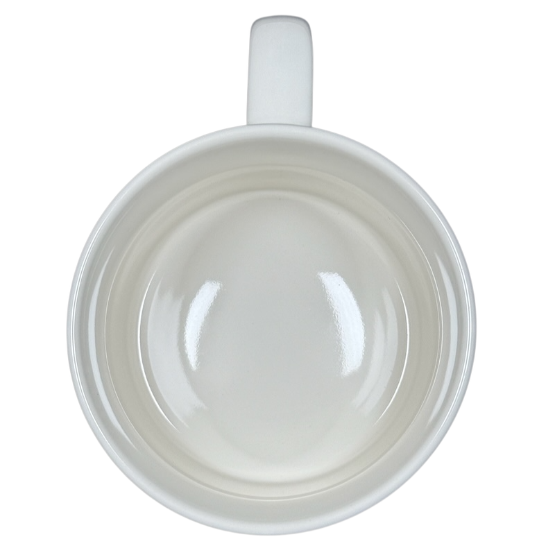 Top view of white ceramic Alexandre Dumas G monogram initial mug empty with handle on black background