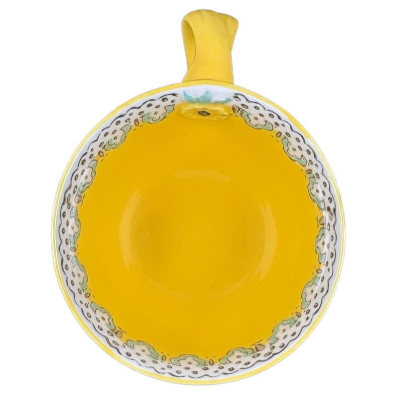 Top view of Anthropologie Elka Ayaka floral pedestal mug bright yellow interior with scalloped floral rim and handle