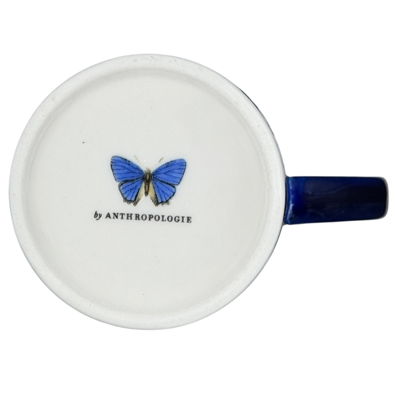 Athalia Butterfly Floral Mug Anthropologie with a blue butterfly design on a white ceramic surface