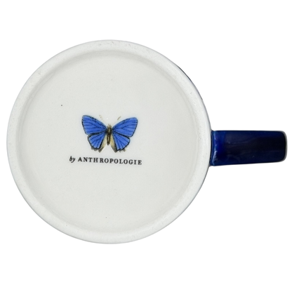 Athalia Butterfly Floral Mug Anthropologie with a blue butterfly design on a white ceramic surface