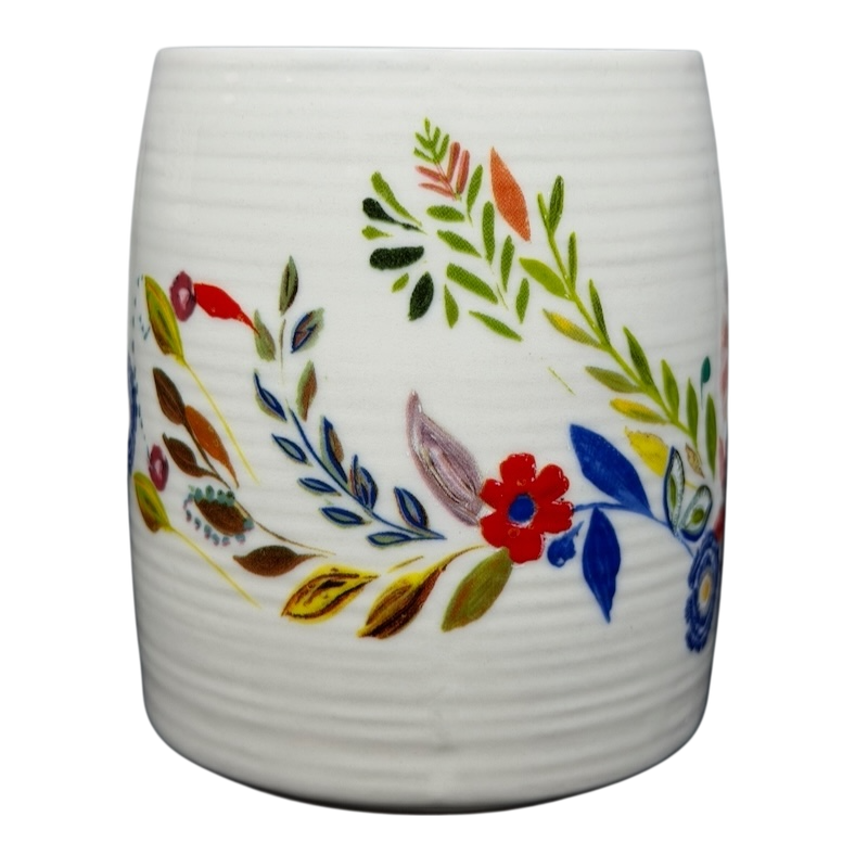 Anthropologie J monogram Starla Halfmann mug featuring colorful floral designs on a textured white background