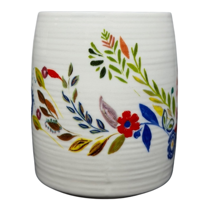 Anthropologie J monogram Starla Halfmann mug featuring colorful floral designs on a textured white background