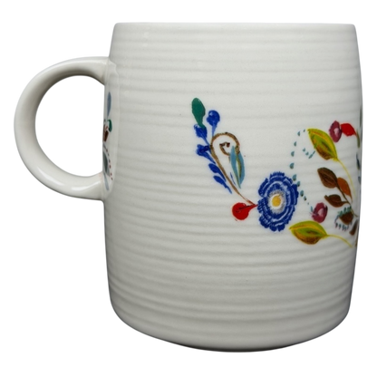 Anthropologie J monogram Starla Halfmann mug with colorful floral designs on a textured white background