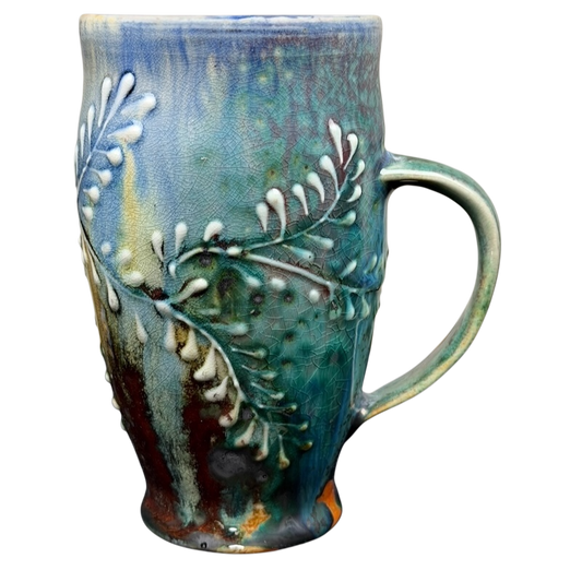 Artisan botanical pottery mug with a unique blue and green glaze featuring intricate leaf designs
