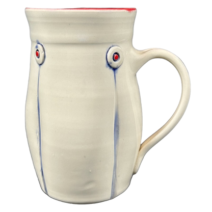 Handmade cream ceramic mug with red interior rim blue drip accents and round embossed buttons Rebecca Lowery embossed pottery mug
