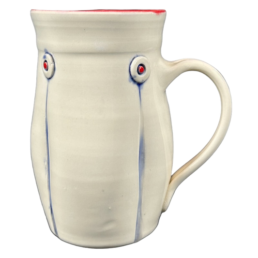 Handmade cream ceramic mug with red interior rim blue drip accents and round embossed buttons Rebecca Lowery embossed pottery mug