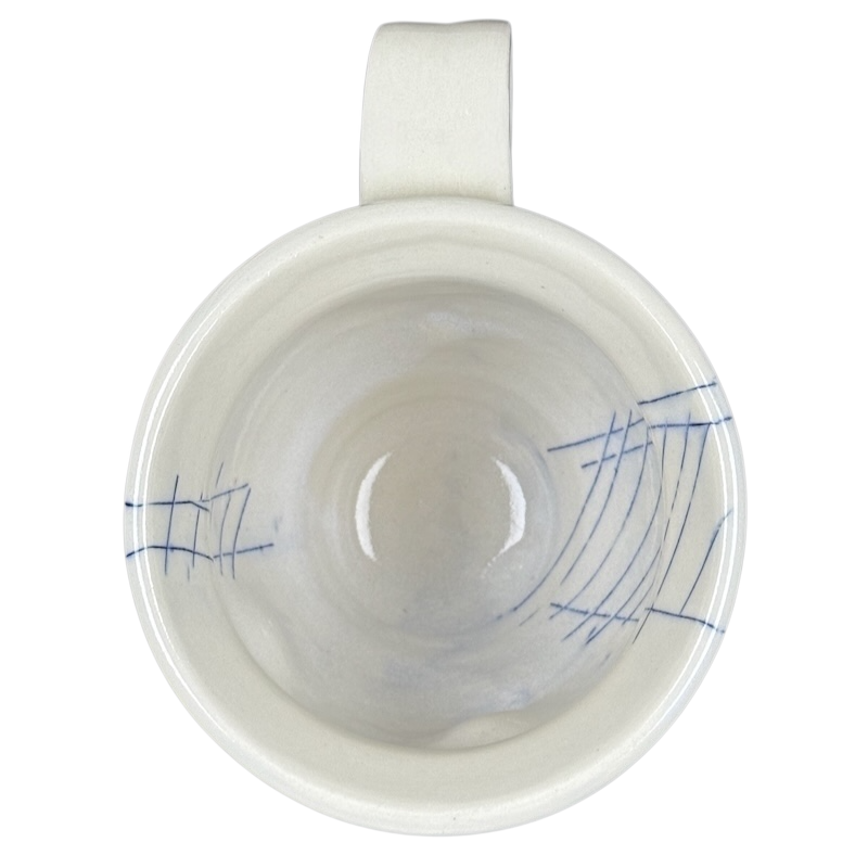 Top view of Vintage abstract blue lines pottery mug white ceramic interior with blue sketch lines and handle visible