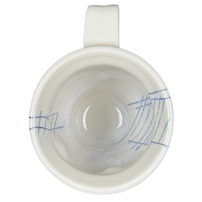 Top view of Vintage abstract blue lines pottery mug white ceramic interior with blue sketch lines and handle visible