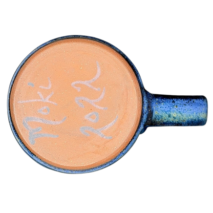 Bottom view of a Blue Speckled Gecko Pottery Mug showcasing its unique orange interior and artistic design