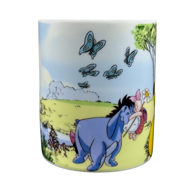 Disney collectible mug Eeyore Piglet featuring characters in a colorful outdoor scene with butterflies and greenery
