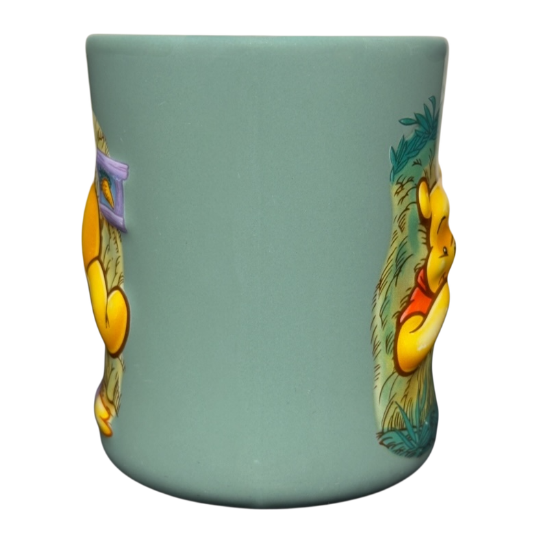 Disney ceramic teal mug with raised artwork of Winnie the Pooh stuck in tree vintage mug showing side views