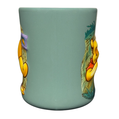 Disney ceramic teal mug with raised artwork of Winnie the Pooh stuck in tree vintage mug showing side views