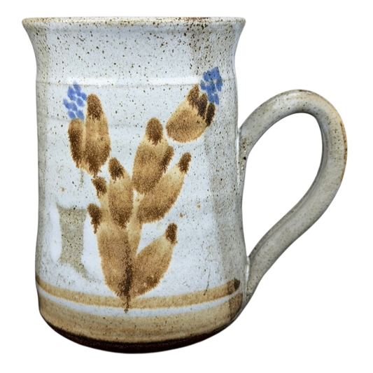 Handcrafted pottery mug with botanical design featuring earthy colors and floral patterns