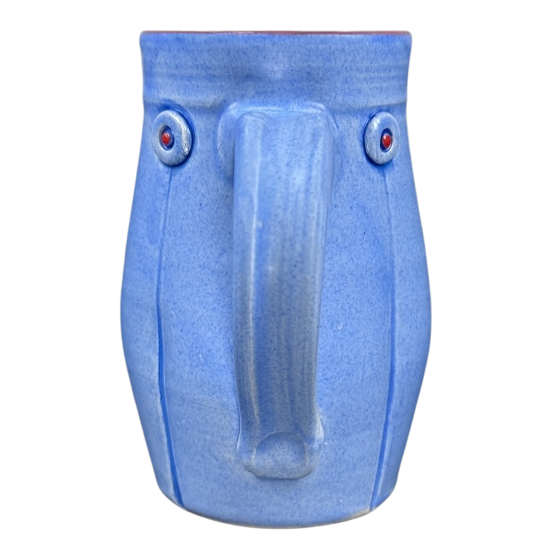 Rebecca Lowery vintage blue pottery mug with face motif central handle like nose and red dot eyes on black background