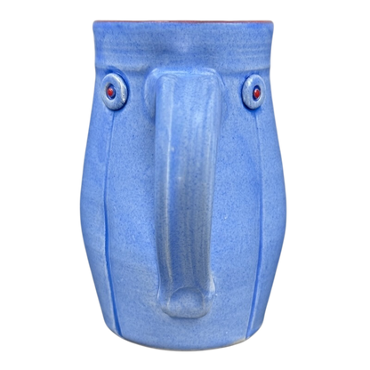 Rebecca Lowery vintage blue pottery mug with face motif central handle like nose and red dot eyes on black background