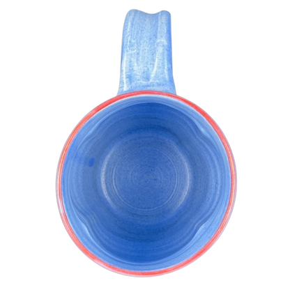 Rebecca Lowery vintage blue pottery mug top down view showing blue glaze red rim and handle on black background