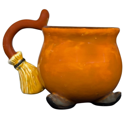 Handmade witch cauldron mug in orange with broomstick handle for whimsical drinkware