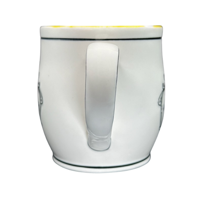 White ceramic Katie Mandy collectible mug with a curved handle and black rim detail