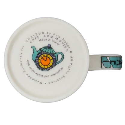Bottom view of Decaf Kris Fisher Chaleur mug showing colorful teapot illustration, maker text and turquoise handle on ceramic