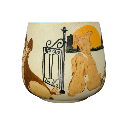 Lady and the Tramp hand-painted pottery mug featuring a sunset scene with the two dogs