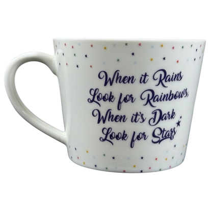 Cooksmart When It Rains Look For Rainbows mug. white ceramic with purple script quote and multicolor star pattern
