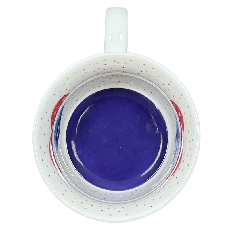 Top view of Cooksmart When It Rains Look For Rainbows mug. White speckled interior with cobalt blue base and rainbow accents