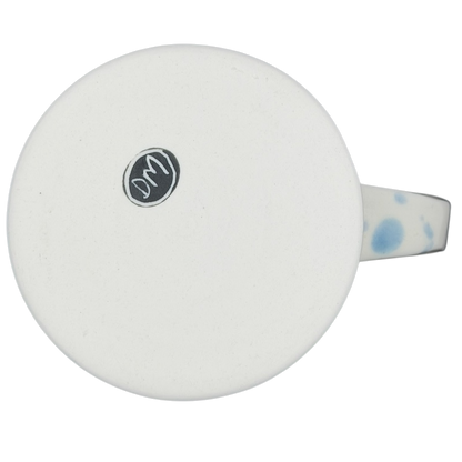 Bottom view of a narwhal signed pottery mug showcasing a smooth white glaze and a decorative handle