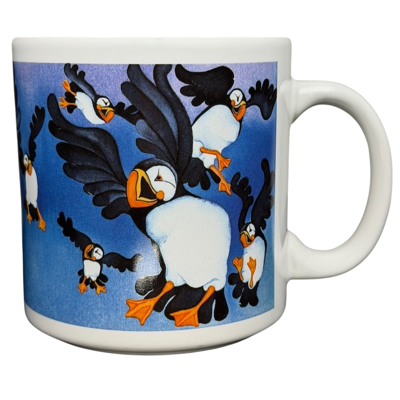 Puffins Barbara Lavallee Mug Arctic Circle Enterprises featuring colorful puffins in flight against a blue background