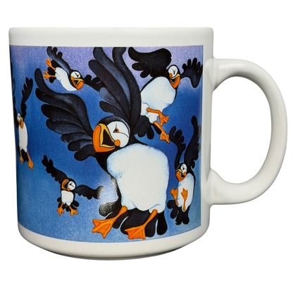 Puffins Barbara Lavallee Mug Arctic Circle Enterprises featuring colorful puffins in flight against a blue background