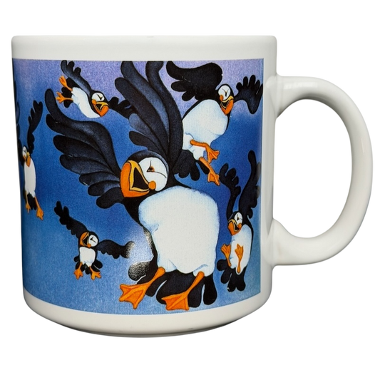 Puffins Barbara Lavallee Mug Arctic Circle Enterprises featuring colorful puffins in flight against a blue background