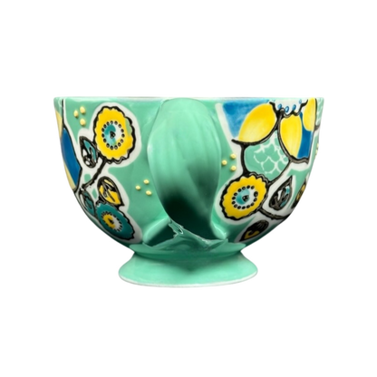 Anthropologie Elka Ayaka green floral pedestal mug with hand painted yellow and blue blooms on glossy ceramic