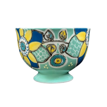 Anthropologie Elka Ayaka green floral pedestal mug with turquoise base and bold yellow and blue flower motifs