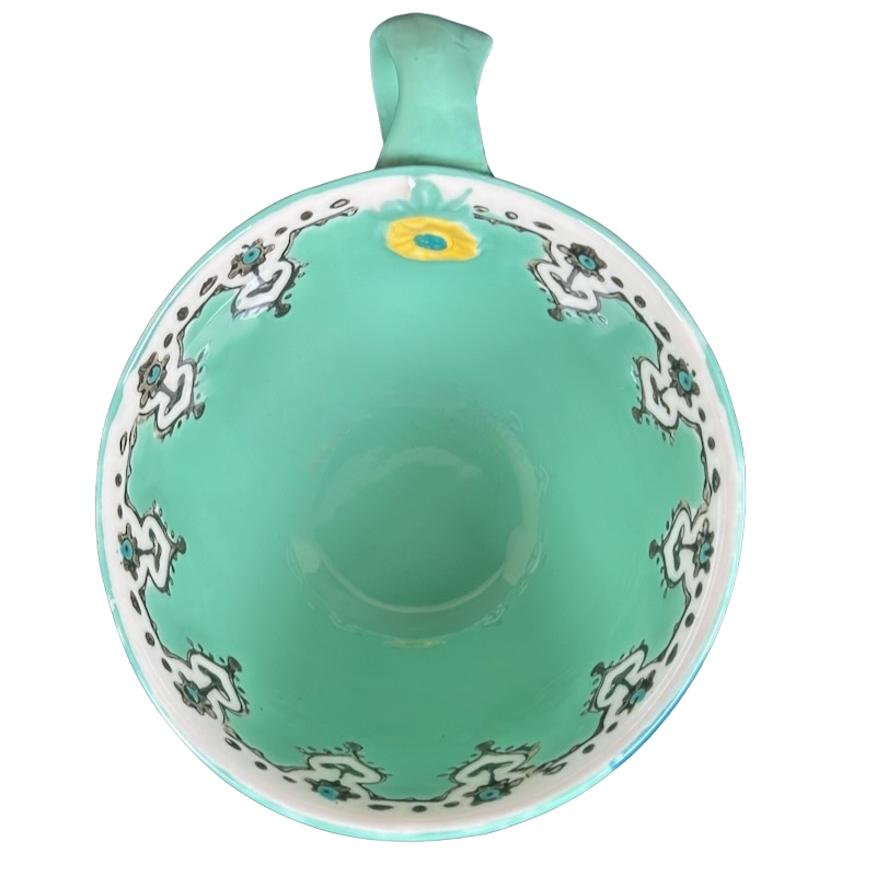 Top view Anthropologie Elka Ayaka green floral pedestal mug showing turquoise interior white floral border and yellow bloom