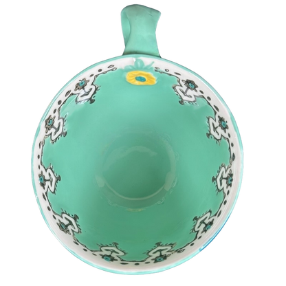 Top view Anthropologie Elka Ayaka green floral pedestal mug showing turquoise interior white floral border and yellow bloom