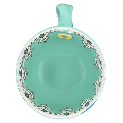 Top view Anthropologie Elka Ayaka green floral pedestal mug turquoise interior with white floral border and handle