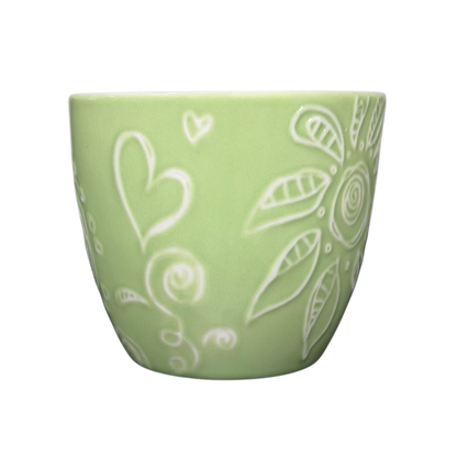 2006 Starbucks embossed green flowers hearts mug showcasing decorative designs on a pastel green background