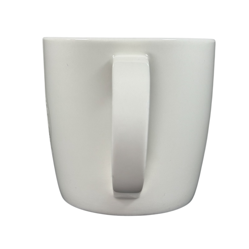 Back view of 2009 Starbucks vintage embossed siren logo mug. White ceramic with centered handle on black background
