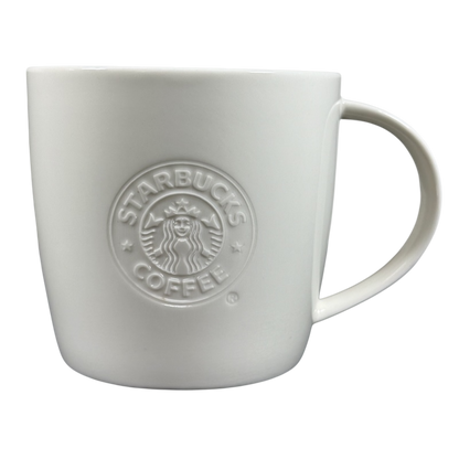 White ceramic 2009 Starbucks vintage embossed siren logo mug with raised siren emblem and rounded handle