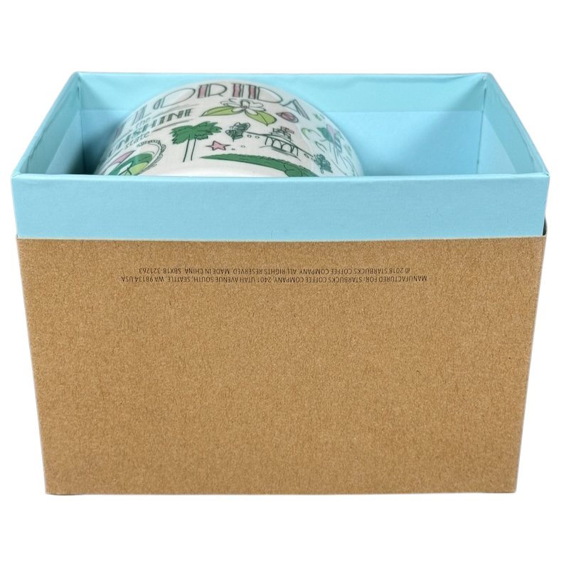 Starbucks Florida Been There mug partially visible inside blue and brown gift box on black background