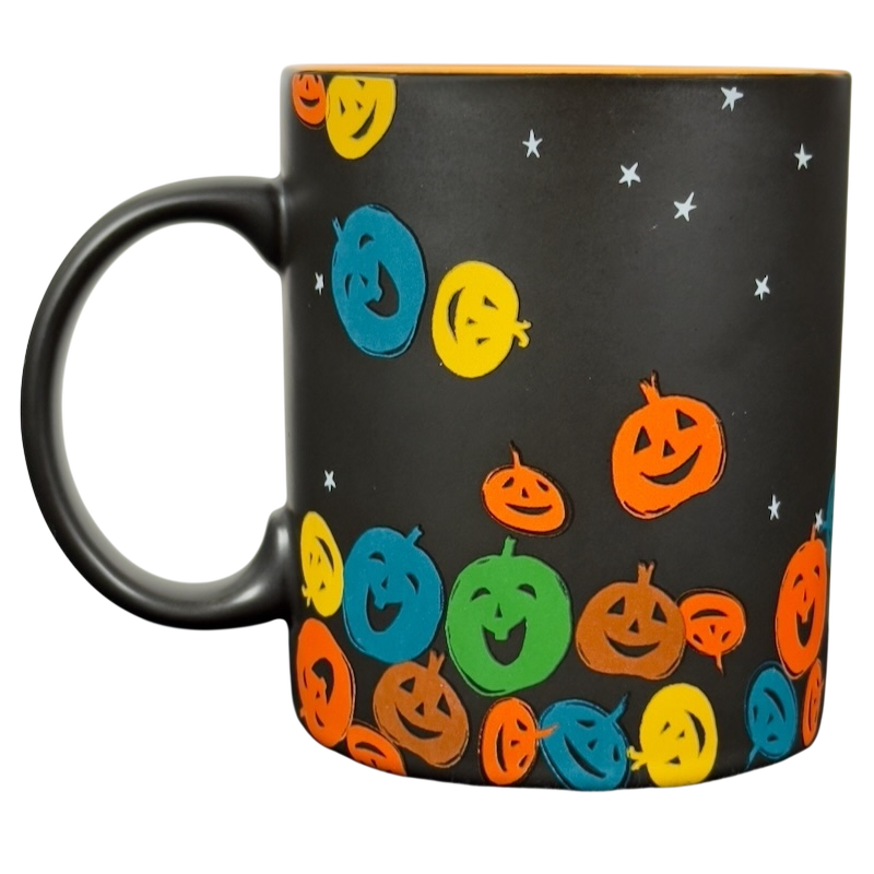 Matte black ceramic vintage Starbucks Halloween pumpkin mug with colorful smiling jack o lantern pattern and orange rim