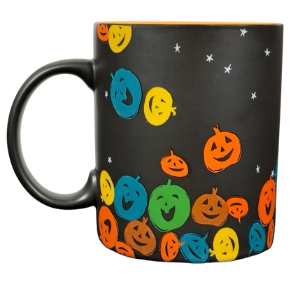 Matte black ceramic vintage Starbucks Halloween pumpkin mug with colorful smiling jack o lantern pattern and orange rim