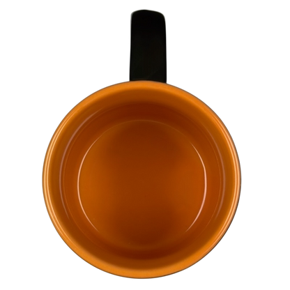 Top view of empty glossy orange ceramic vintage Starbucks Halloween pumpkin mug with black handle on black background