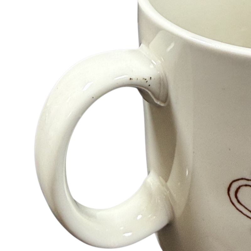 Close up of white ceramic handle and partial heart motif on black background Taylor & Ng Le Chat vintage mug