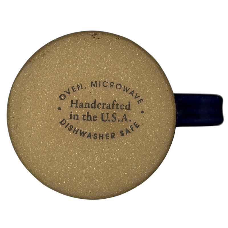 The Broadmoor Colorado Pottery Mug with tan finish and blue handle, dishwasher safe and handcrafted in the USA