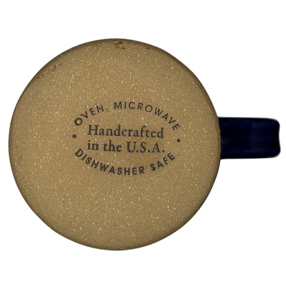 The Broadmoor Colorado Pottery Mug with tan finish and blue handle, dishwasher safe and handcrafted in the USA