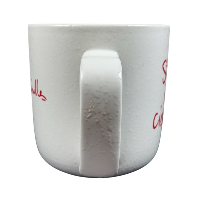White ceramic Sara Bareilles tour mug with speckled texture and centered handle on black background