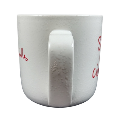 White ceramic Sara Bareilles tour mug with speckled texture and centered handle on black background