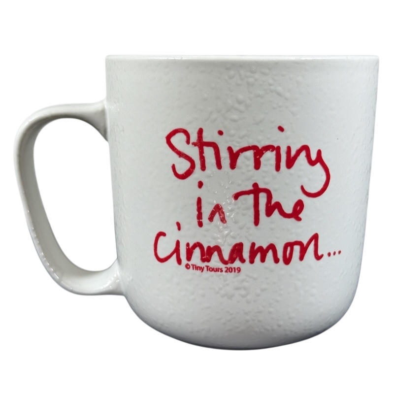 White textured ceramic mug with red handwritten Stirring in the cinnamon text on front Sara Bareilles tour mug
