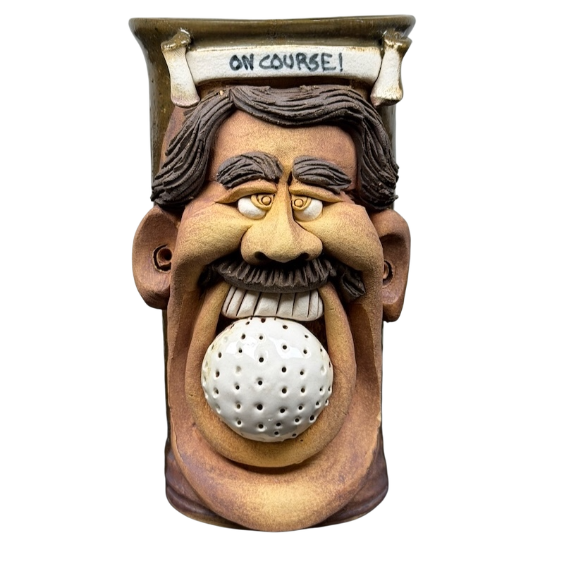 Ugly face pottery golf mug featuring a smiling man's face with a golf ball in his mouth