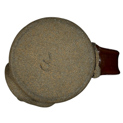 Bottom view of an ugly face pottery vintage winking mug showing textured base and brown handle